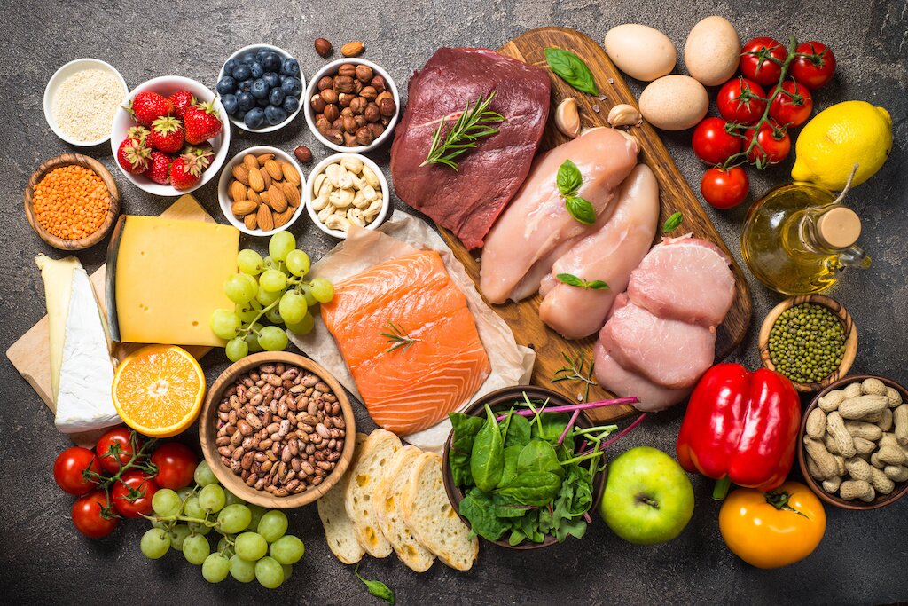 Balanced diet food background. Healthy nutrition. Ketogenic low carbs diet. Meat, fish, nuts, vegetables, oil, beans, lentils fruits and berries on dark background. Top view.