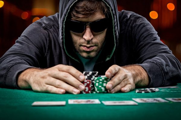 Ma with sunglasses pushing chips in the middle of the table