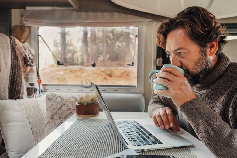 Man on a train with laptop and coffee mug