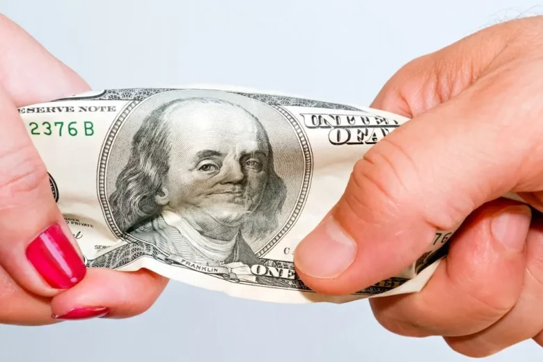 two hands stretching a one dollar bill