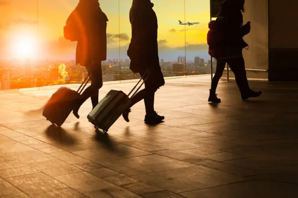 two people rolling their bags through an airport