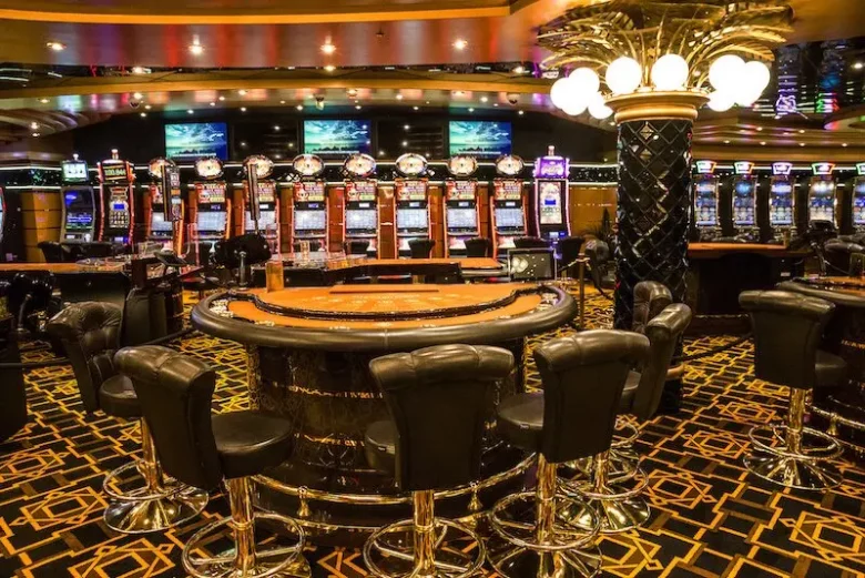 The inside of a casino with slots and a poker table