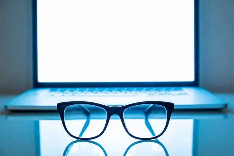 blue glasses in front of a laptop