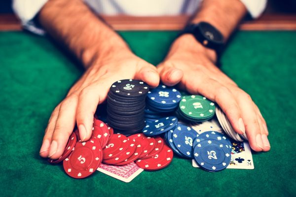 A mand with a black watch tilting and pushing his chips in the middle of the poker table