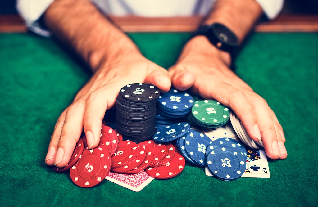 A mand with a black watch tilting and pushing his chips in the middle of the poker table