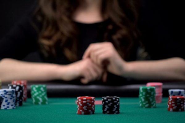 girl putting chips in the middle of a poker table with a check-raise