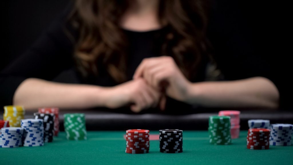 girl putting chips in the middle of a poker table with a check-raise