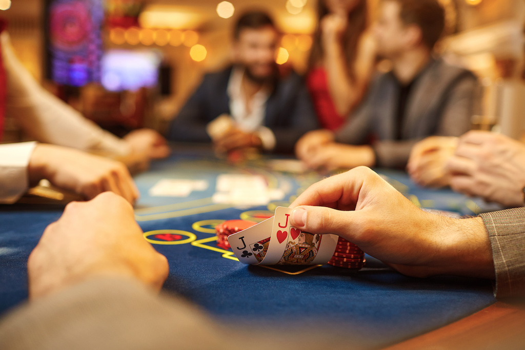 People play poker at the table in the casino. Hands with cards in the hands of a game in a casino.