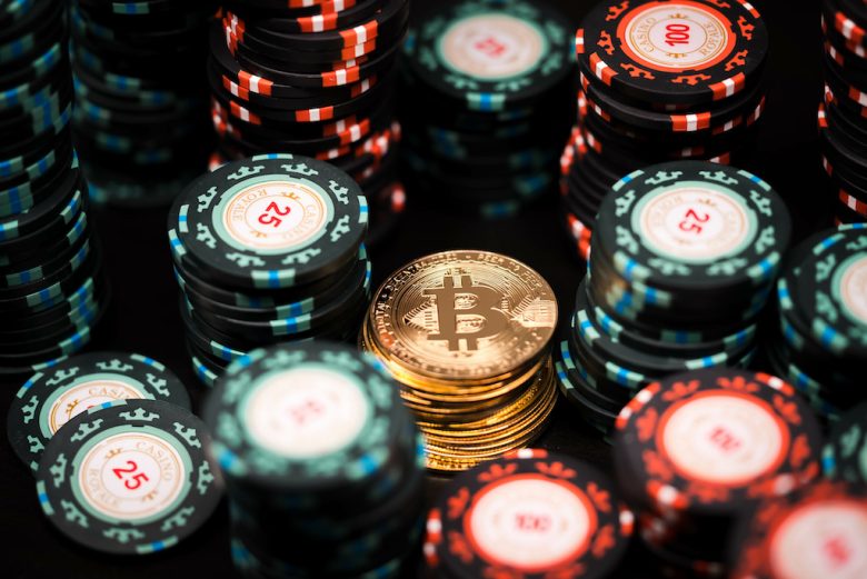 Close-up of a stack of bitcoin coins on the background of a stack of casino chips. Bitcoin casino game. Cryptocurrency excitement. Bet on bitcoins.