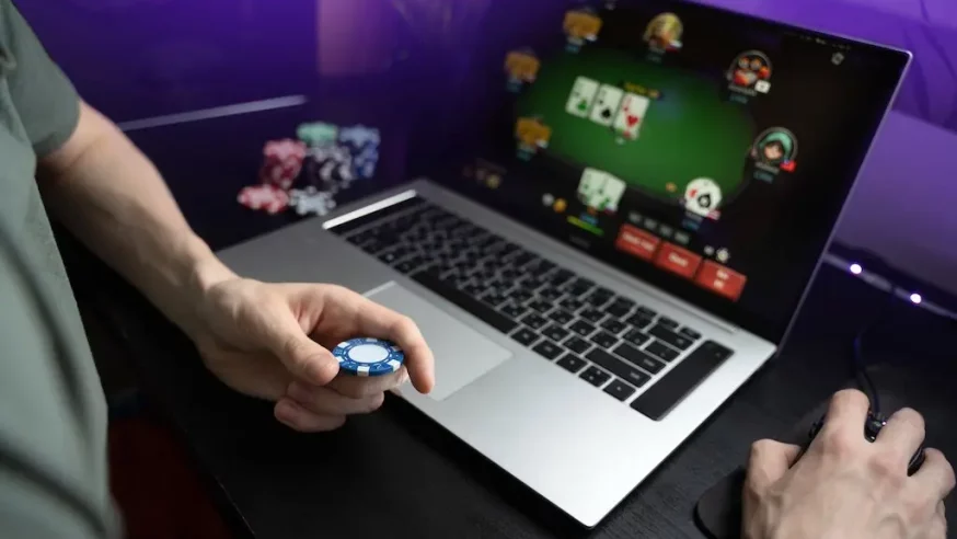 man holding poker chip while playing online poker