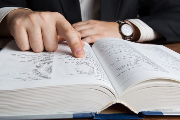 man looking in the large dictionary close up for poker terms