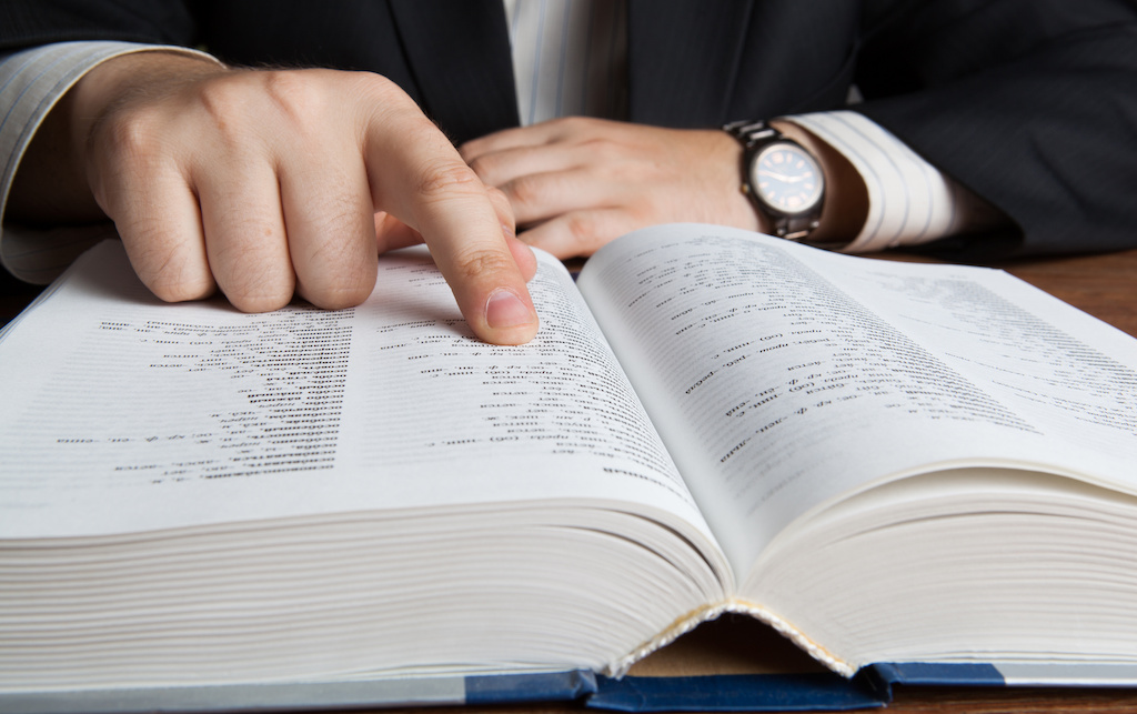 man looking in the large dictionary close up for poker terms