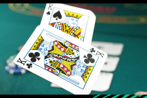 King of Spades and a King of Clubs being tossed on to a poker table.