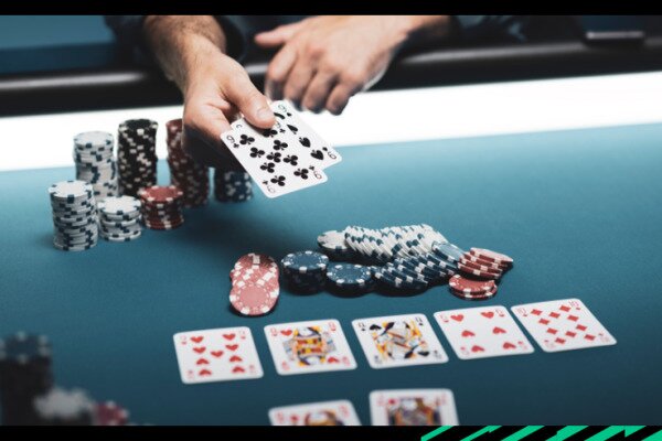 Cards being displayed on a poker table with poker chips stacked.