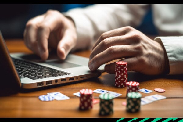 Someone learning how to play poker on their laptop, with poker chips on their desk.