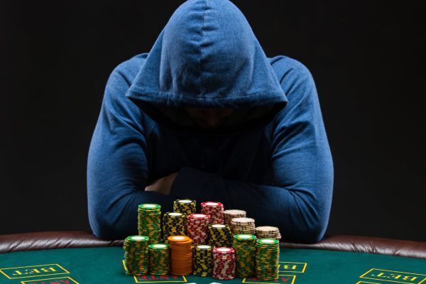 A poker player wearing a hoodie at a poker table with chips in front of him