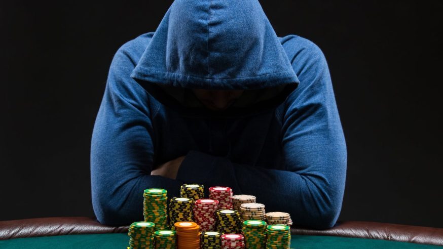 A poker player wearing a hoodie at a poker table with chips in front of him