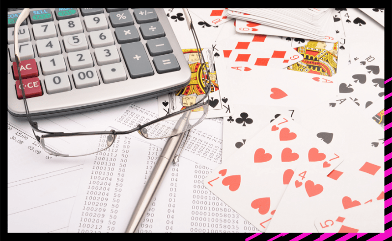 Playing cards laid out with a calculator, glasses and a pen for calculating poker odds.