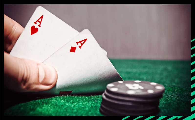 A pair of aces (hearts and diamond) on a poker table with poker chips representing poket aces.