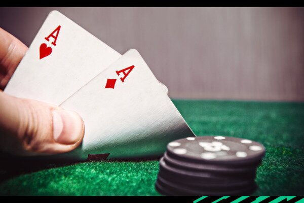 A pair of aces (hearts and diamond) on a poker table with poker chips representing poket aces.