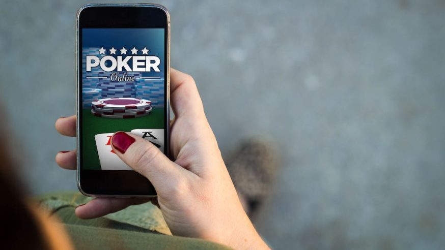 womans hand holding a phone playing poker