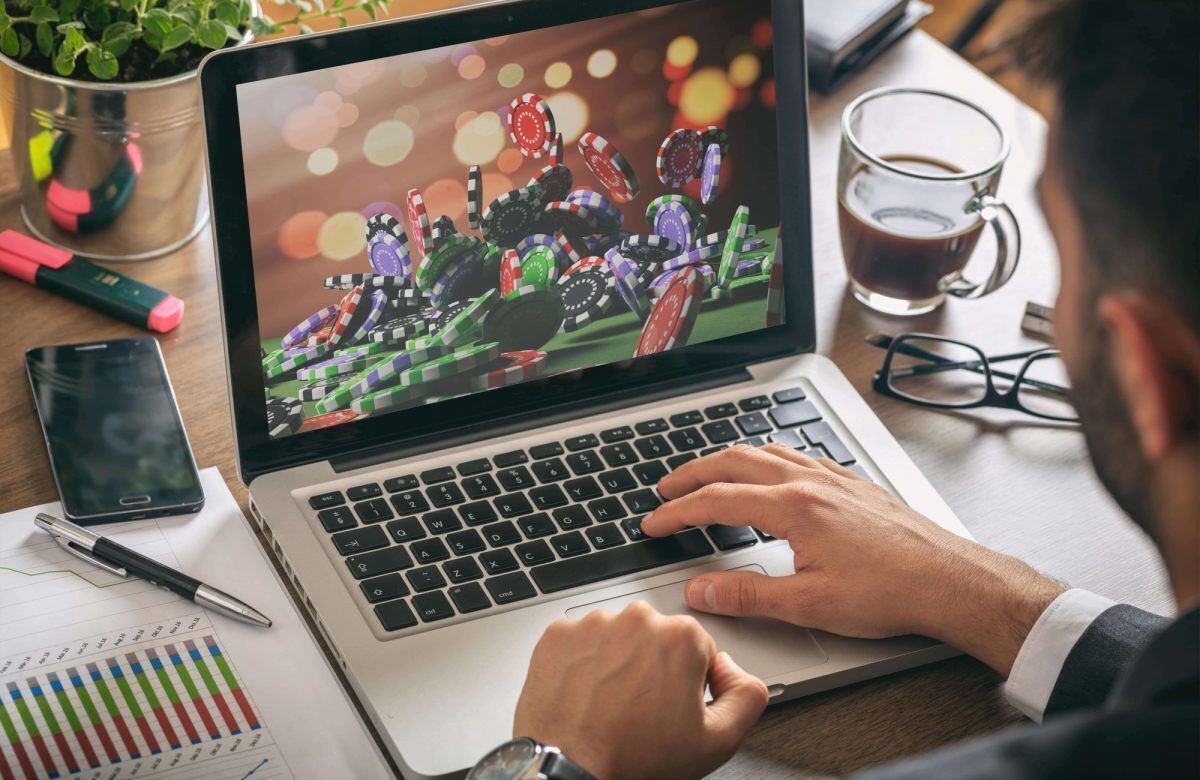 A laptop with an image of a big pile of poker chips next to a paper with graphs