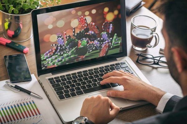 A laptop with an image of a big pile of poker chips next to a paper with graphs