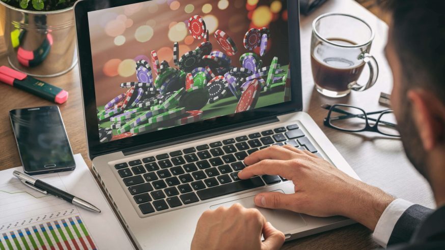 A laptop with an image of a big pile of poker chips next to a paper with graphs